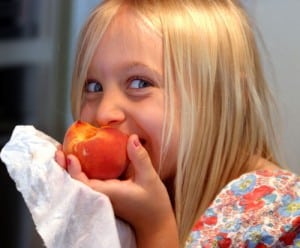 Blonde girl eating peach