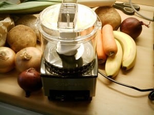 food processor surrounded by carrots and bananas
