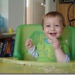 baby eating spaghetti in the highchair.