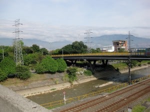 river, train tracks, bridge with Medellin hills in background